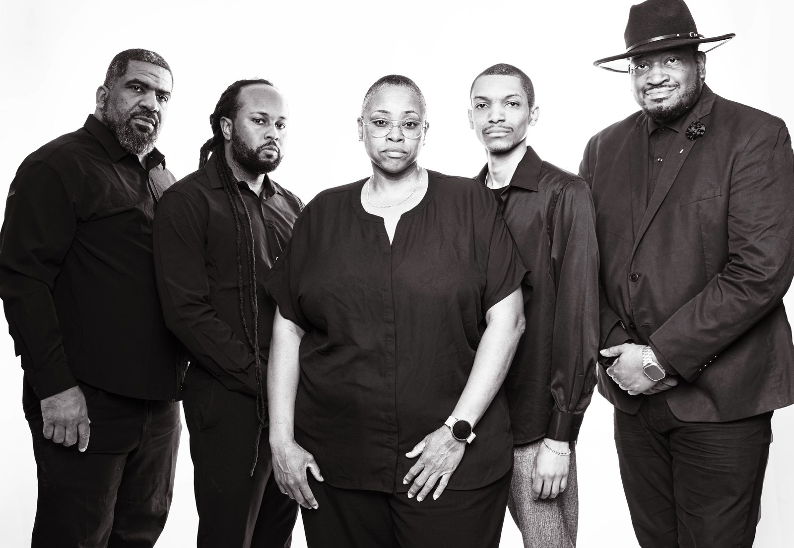 Five members of the team dressed in black against a white studio background.